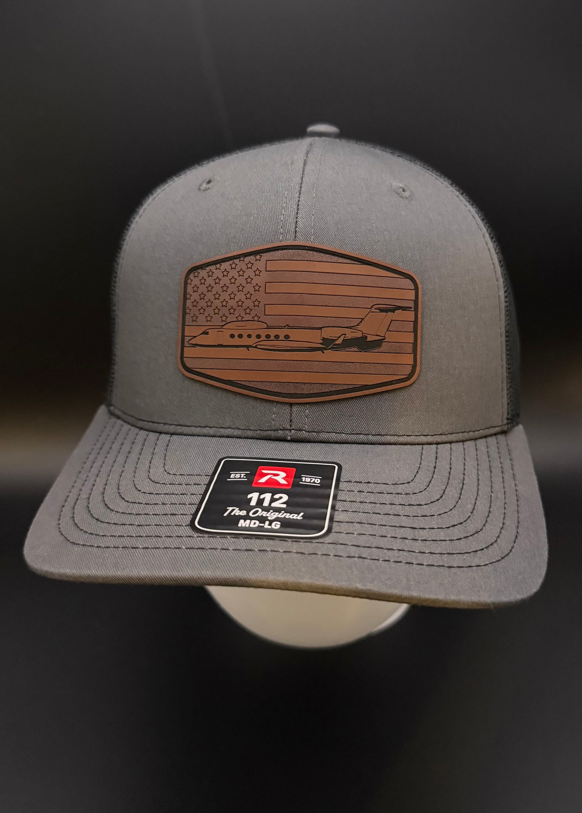 Gray cap with American flag patch and logo on a dark background